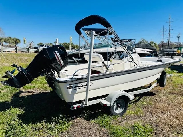 Slide: The Image of 2010 Boston Whaler 150 Montauk boat on trailer, parked on grass. - 2