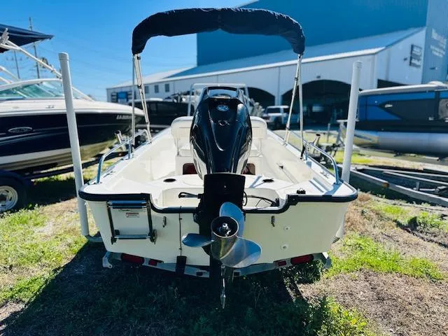 Slide: The Image of 2010 Boston Whaler 150 Montauk boat, rear view with outboard motor, parked outdoors. - 8
