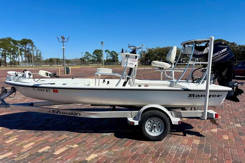 Slide: The Image of 2009 Ranger Banshee boat on trailer, parked on brick pavement under clear blue sky. - 14