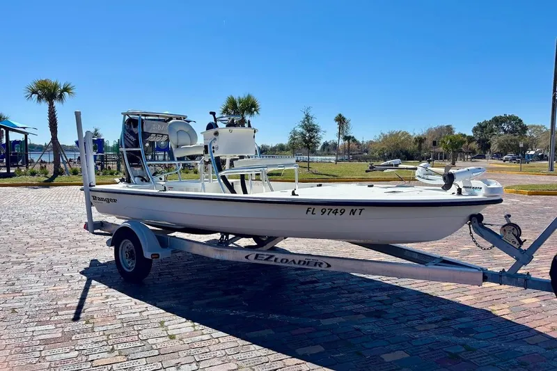 Slide: The Image of 2009 Ranger Banshee boat on trailer, parked on brick pavement under clear blue sky. - 2