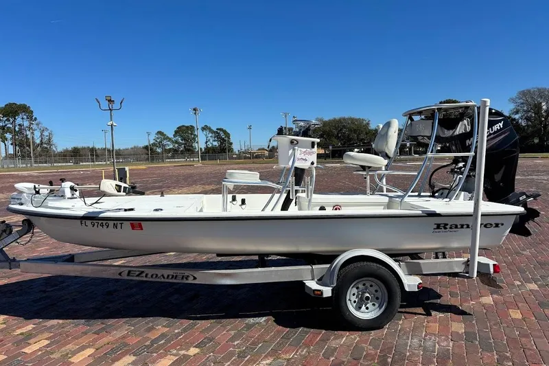 Slide: The Image of 2009 Ranger Banshee boat on trailer, parked on brick pavement under clear blue sky. - 3