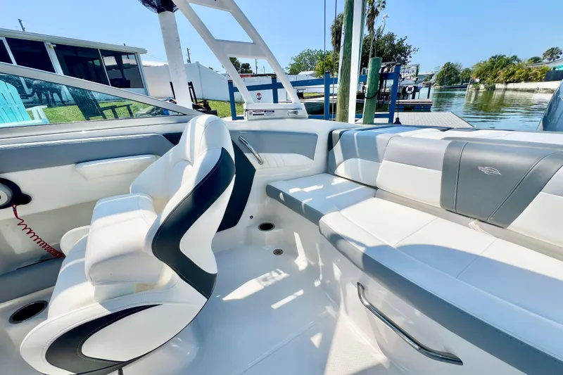Slide: The Image of 2023 Chaparral 23 SSi OB boat interior with white and gray seating, docked by the water. - 17
