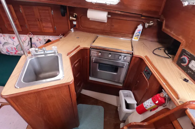 Slide: The Image of Cozy 1982 Irwin 34 Citation yacht kitchen with sink, stove, and wooden cabinetry. - 11