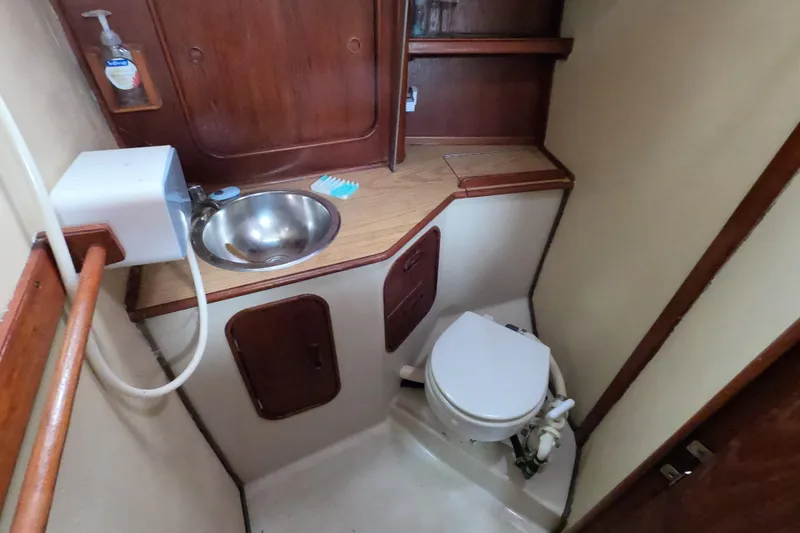 Slide: The Image of 1982 Irwin 34 Citation yacht bathroom with sink, toilet, and wooden cabinetry. - 19