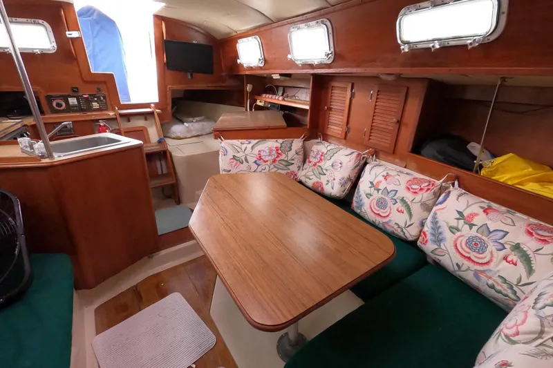 Slide: The Image of 1982 Irwin 34 Citation yacht interior with wooden table, floral cushions, and compact kitchen area. - 22