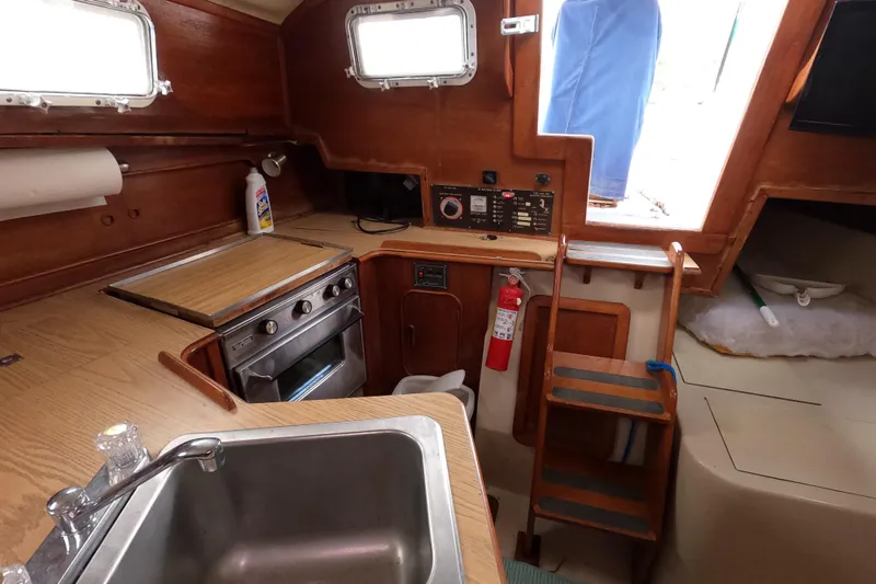 Slide: The Image of 1982 Irwin 34 Citation yacht interior with kitchen, stove, sink, and wooden cabinetry. - 23