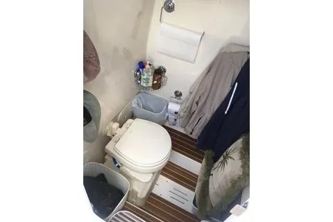 Slide: The Image of 2018 Scout 255 LXF boat bathroom with toilet, storage, and wooden flooring. - 11