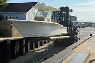 Slide: The Image of 2018 Scout 255 LXF boat being lifted by a forklift at a marina. - 13