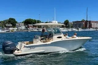 Slide: The Image of 2018 Scout 255 LXF boat cruising in a sunny harbor with passengers onboard. - 14