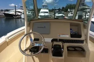 Slide: The Image of 2018 Scout 255 LXF boat dashboard with steering wheel and controls at marina. - 8