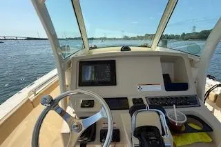 Slide: The Image of 2018 Scout 255 LXF boat dashboard with steering wheel, controls, and navigation screen on open water. - 9