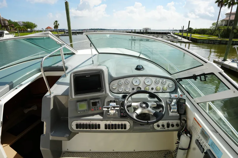 Slide: The Image of 2005 CRUISERS YACHT 340 Express helm with navigation controls and waterfront view. - 11