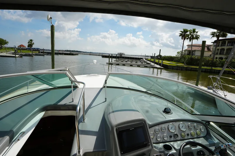 Slide: The Image of 2005 CRUISERS YACHT 340 Express helm view, docked in a scenic marina. - 12