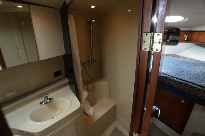 Slide: The Image of 2005 CRUISERS YACHT 340 Express bathroom with sink, shower, and adjacent cabin bed. - 18