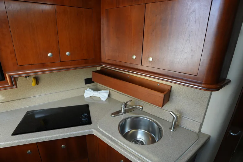 Slide: The Image of 2005 CRUISERS YACHT 340 Express kitchen with wooden cabinets, sink, and stovetop. - 22