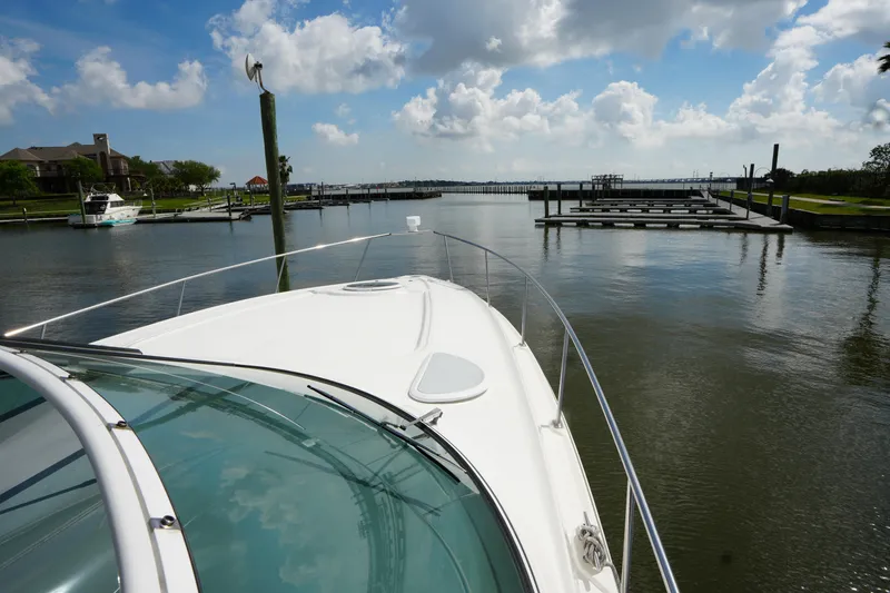 Slide: The Image of 2005 Cruisers Yacht 340 Express navigating calm marina waters under a partly cloudy sky. - 6