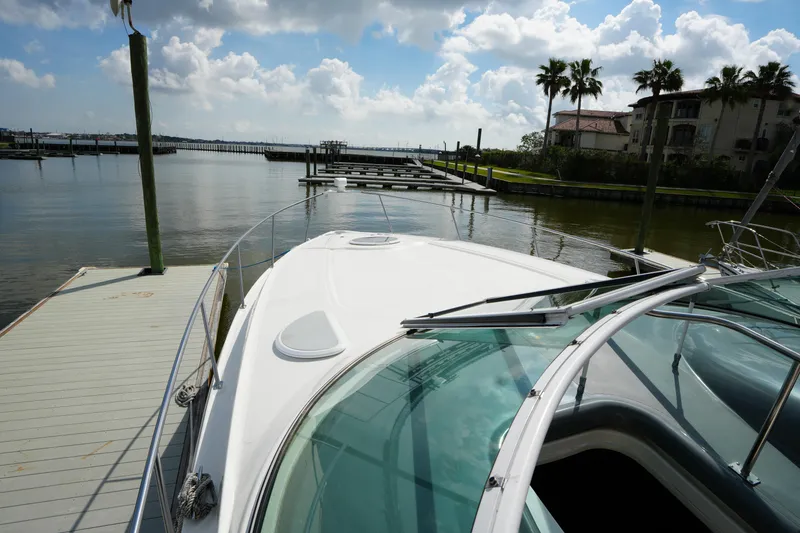 Slide: The Image of 2005 CRUISERS YACHT 340 Express docked by a serene waterfront with palm trees. - 7