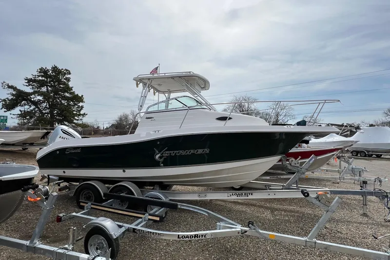 The Image of 2006 Striper 2301 Walkaround OB boat on trailer, parked outdoors. - 0