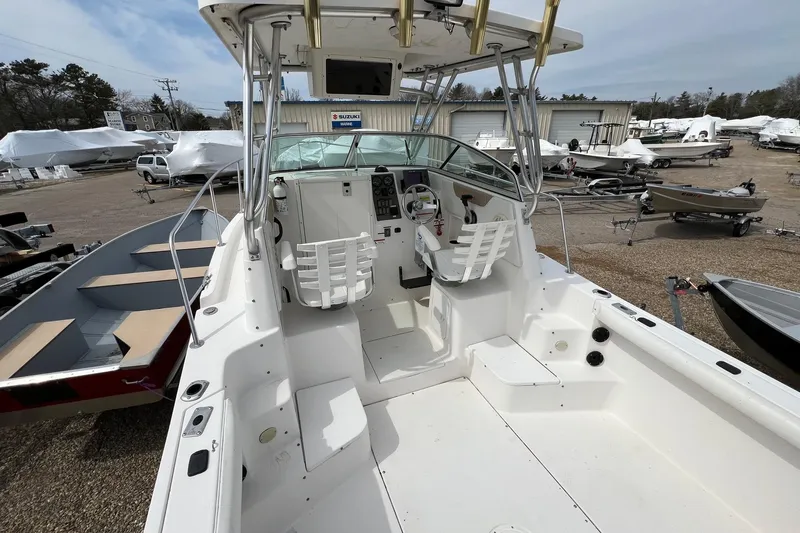 Slide: The Image of 2006 Striper 2301 Walkaround OB boat interior with helm and seating, parked outdoors. - 23