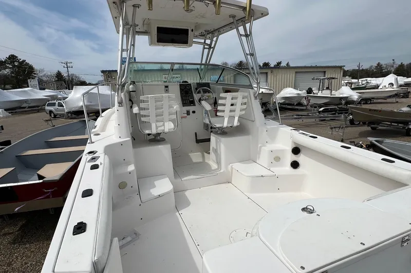 Slide: The Image of 2006 Striper 2301 Walkaround OB boat interior with helm and seating, parked outdoors. - 25