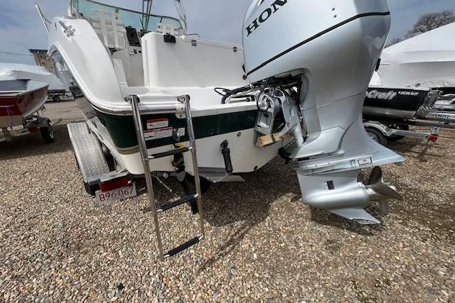 Slide: The Image of 2006 Striper 2301 Walkaround OB with Honda outboard motor and ladder on gravel. - 32