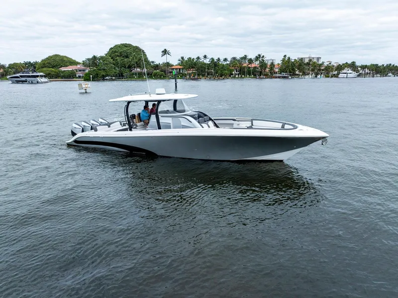 The Image of 2020 Fountain 43NX boat cruising on a calm lake with scenic shoreline. - 0