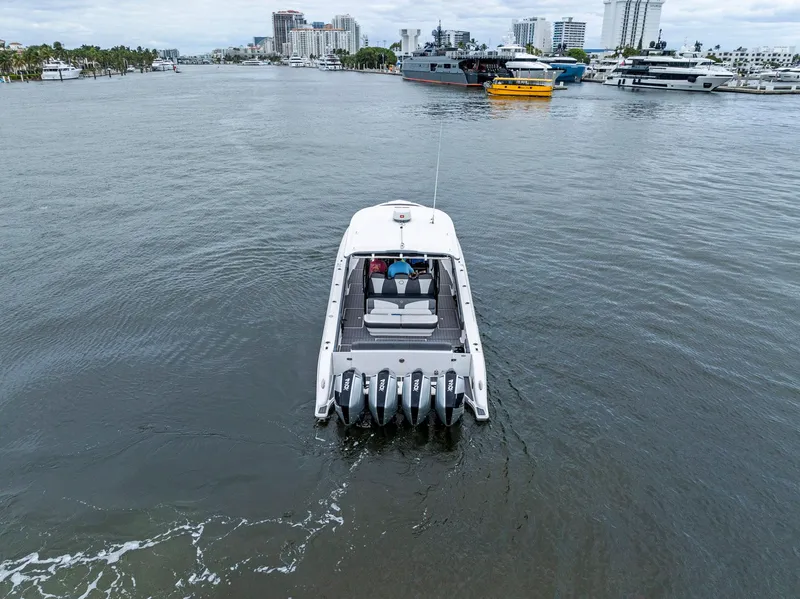 Slide: The Image of 2020 Fountain 43NX boat cruising in a marina with cityscape background. - 40