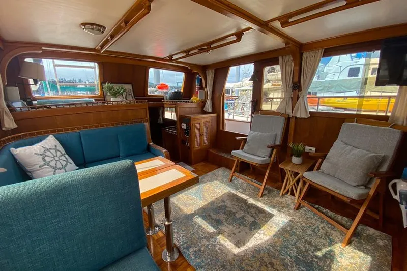 Slide: The Image of 1980 CHB Trawler interior with cozy seating, wooden accents, and nautical decor. - 10