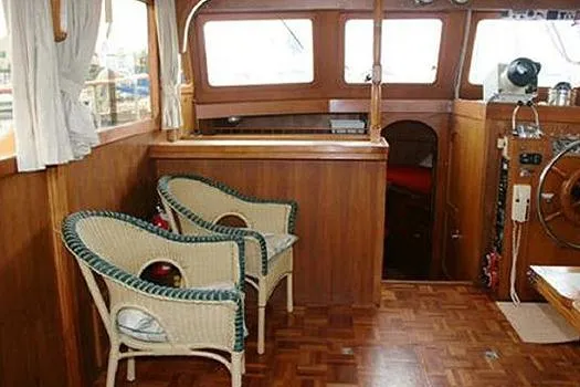 Slide: The Image of Interior of a 1980 CHB Trawler with wicker chairs and wooden paneling. - 11