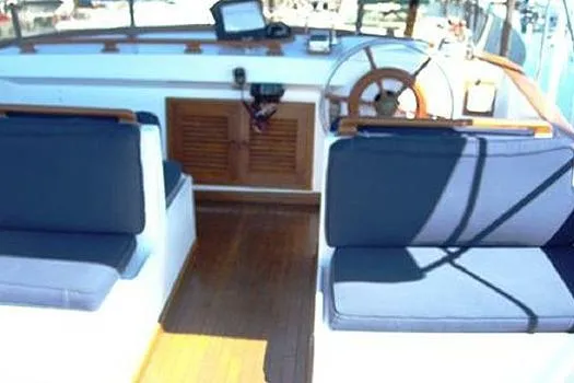 Slide: The Image of 1980 CHB Trawler interior with blue cushioned seating and wooden steering wheel. - 2