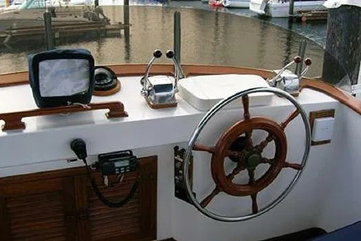 Slide: The Image of 1980 CHB Trawler helm with wooden wheel, navigation equipment, and controls at marina. - 3