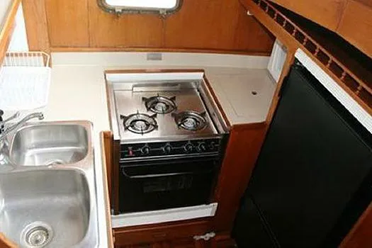 Slide: The Image of 1980 CHB Trawler kitchen with stove, sink, and refrigerator. - 5