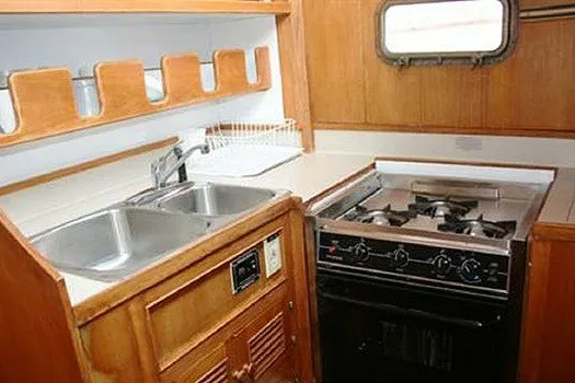 Slide: The Image of 1980 CHB Trawler kitchen with dual sink, stove, and wooden cabinetry. - 14