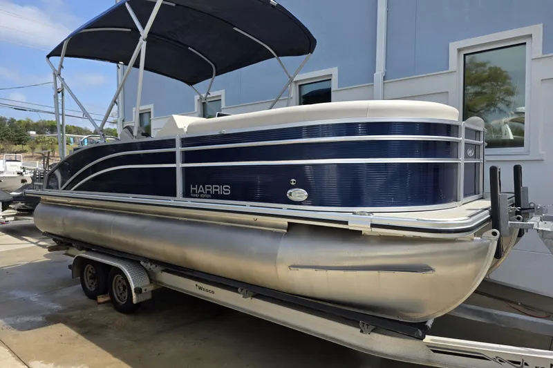 The Image of 2021 Harris Cruiser 230 pontoon boat on trailer, blue and white design. - 0