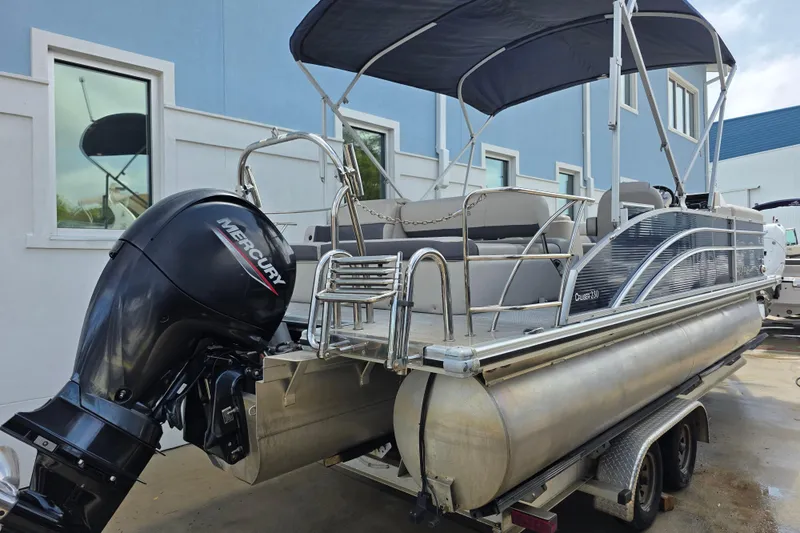 Slide: The Image of 2021 Harris Cruiser 230 pontoon boat with Mercury outboard motor, parked on a trailer. - 3