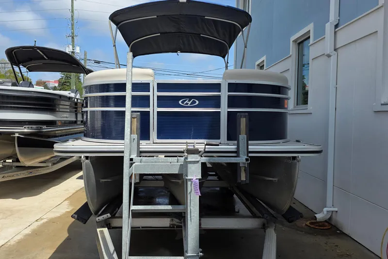 Slide: The Image of 2021 Harris Cruiser 230 pontoon boat on trailer, blue and white exterior. - 4