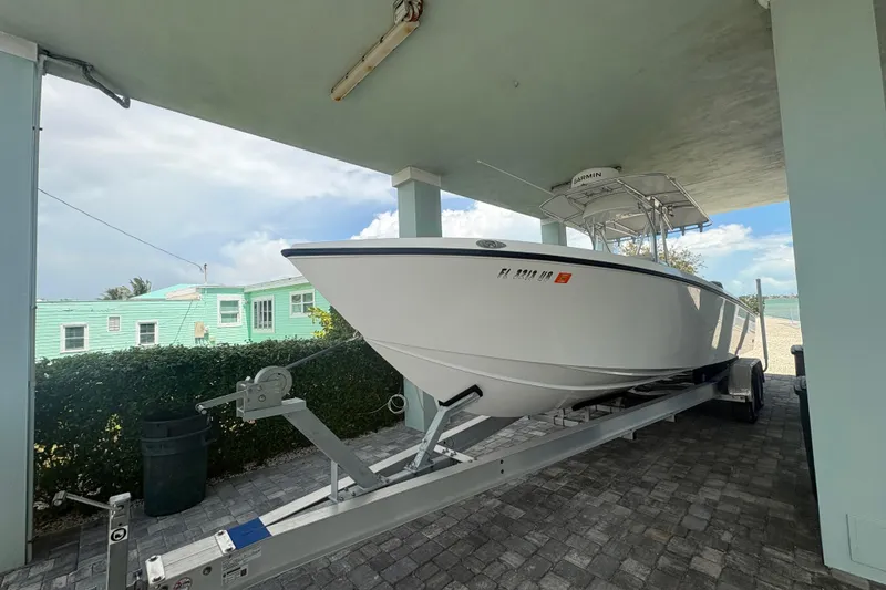 The Image of 2025 Whitewater 28 boat on trailer under shelter, with clear sky background. - 1