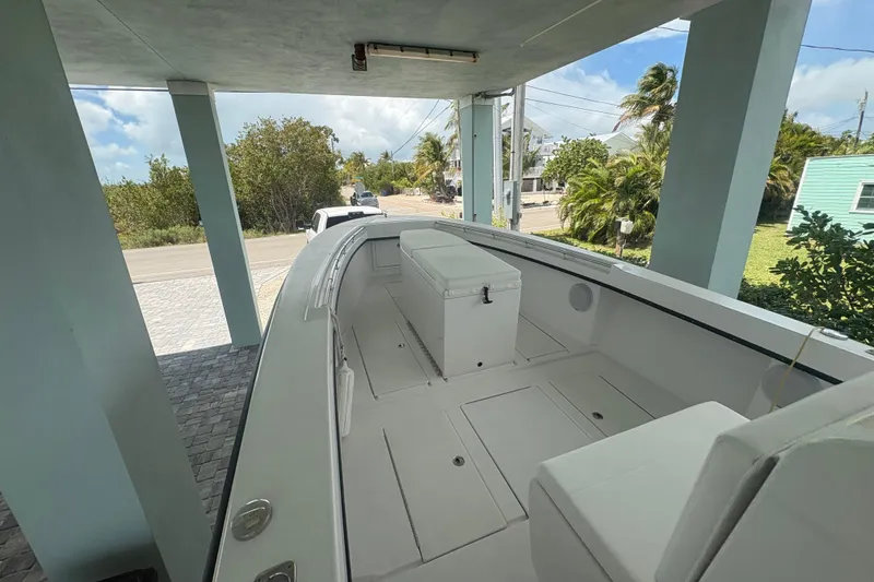 Slide: The Image of 2025 Whitewater 28 boat parked under a covered area, showcasing spacious deck and seating. - 14