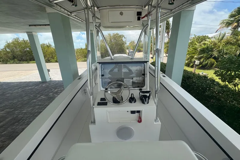 Slide: The Image of 2025 Whitewater 28 boat cockpit with steering wheel and controls, parked under a canopy. - 9