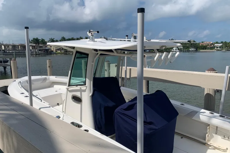 Slide: The Image of 2009 Boston Whaler 280 Outrage docked by waterfront, featuring covered seating and fishing rod holders. - 2