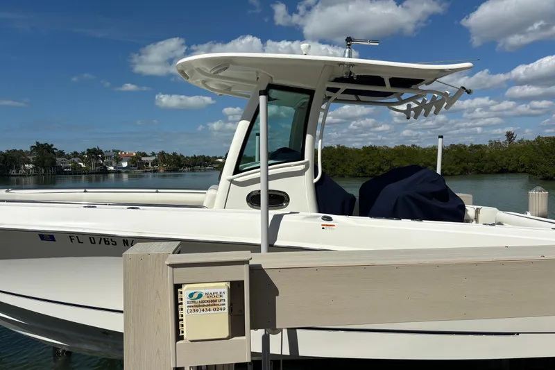 Slide: The Image of 2009 Boston Whaler 280 Outrage docked, clear sky, calm waters, lush greenery backdrop. - 5