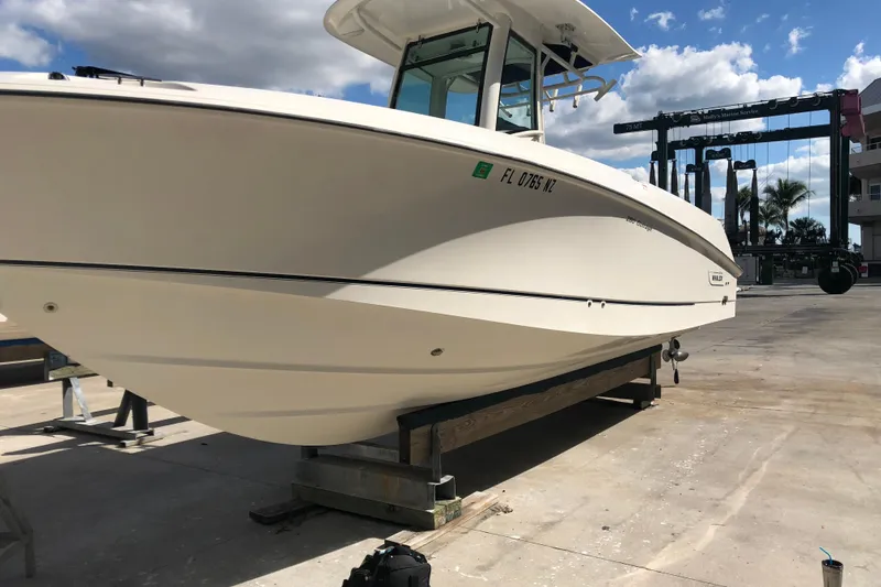 Slide: The Image of 2009 Boston Whaler 280 Outrage boat on dry dock under a partly cloudy sky. - 6