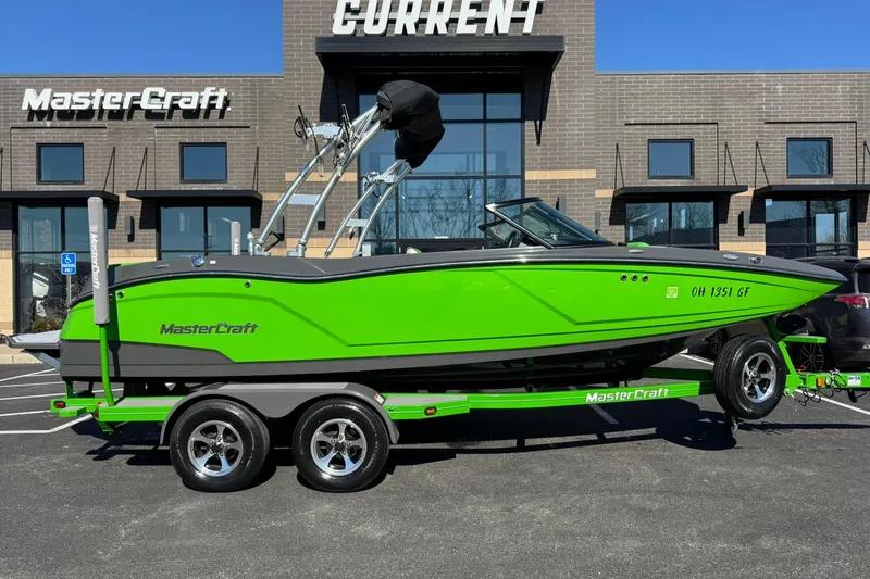 The Image of 2015 MasterCraft NXT20 boat in vibrant green on a trailer, parked outside dealership. - 1