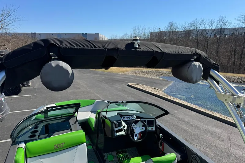 Slide: The Image of 2015 MasterCraft NXT20 boat with green interior and black canopy, parked near water. - 13