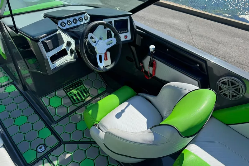 Slide: The Image of Interior of a 2015 MasterCraft NXT20 boat with green accents and modern controls. - 15