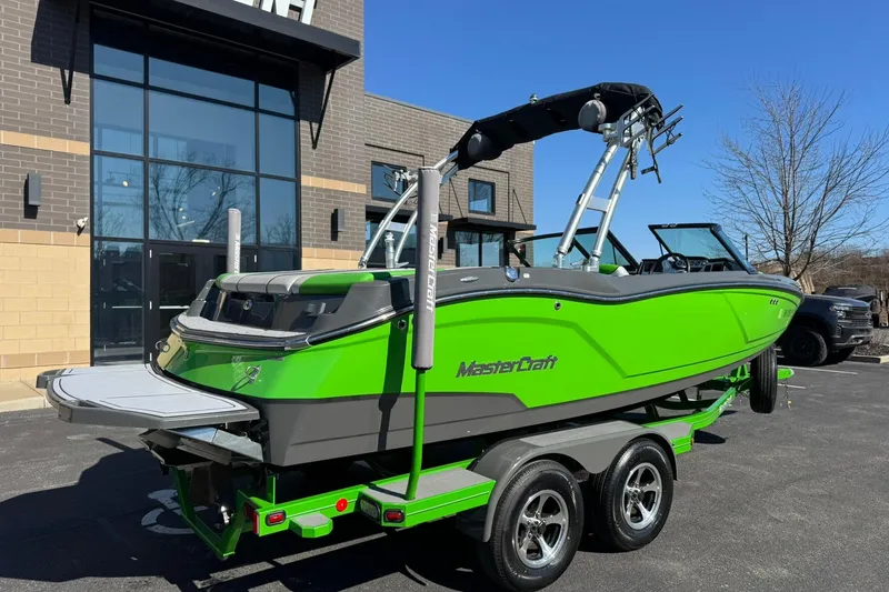 Slide: The Image of 2015 MasterCraft NXT20 boat in vibrant green on a trailer outside a building. - 4