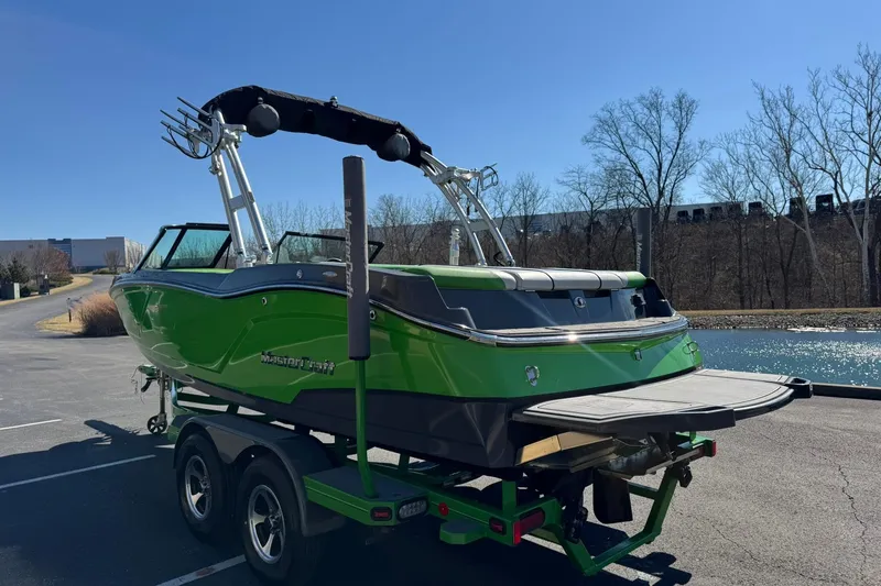 Slide: The Image of 2015 MasterCraft NXT20 boat in vibrant green on a trailer by a lake. - 6