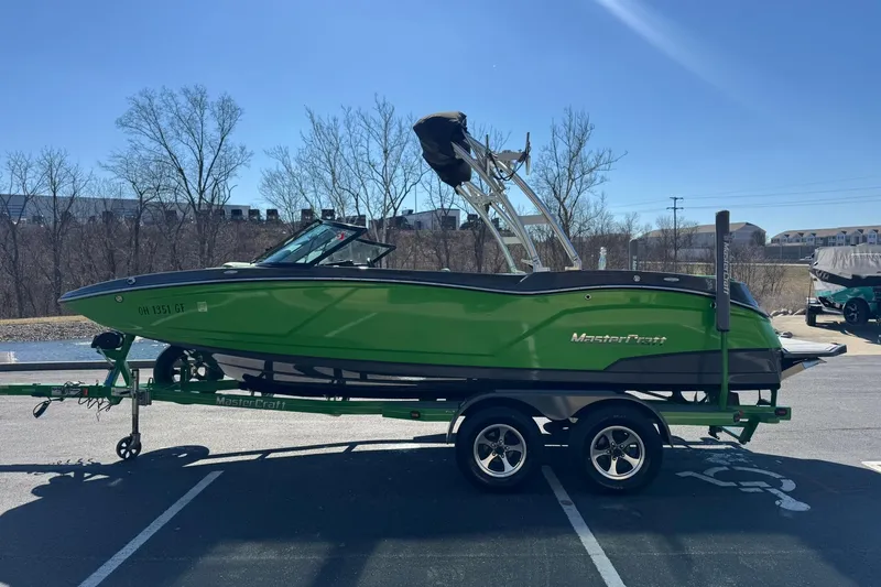 Slide: The Image of 2015 MasterCraft NXT20 boat in vibrant green on a trailer, parked outdoors. - 7