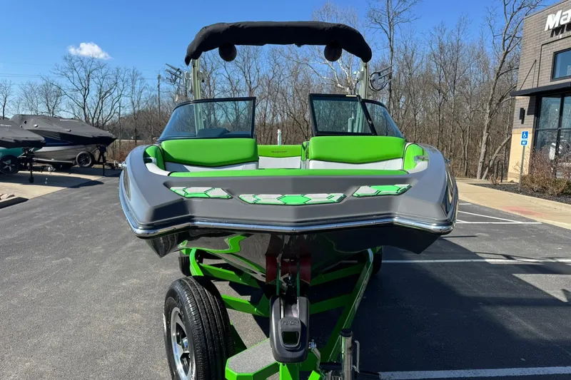 Slide: The Image of 2015 MasterCraft NXT20 boat with green accents on a trailer in a parking lot. - 9