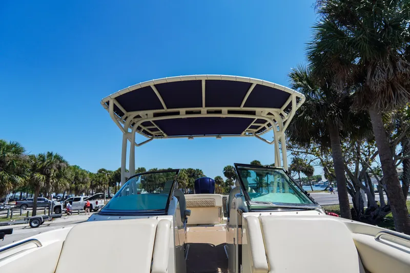 Slide: The Image of 2017 Chris-Craft Calypso 26 boat with canopy, parked near palm trees under clear blue sky. - 23